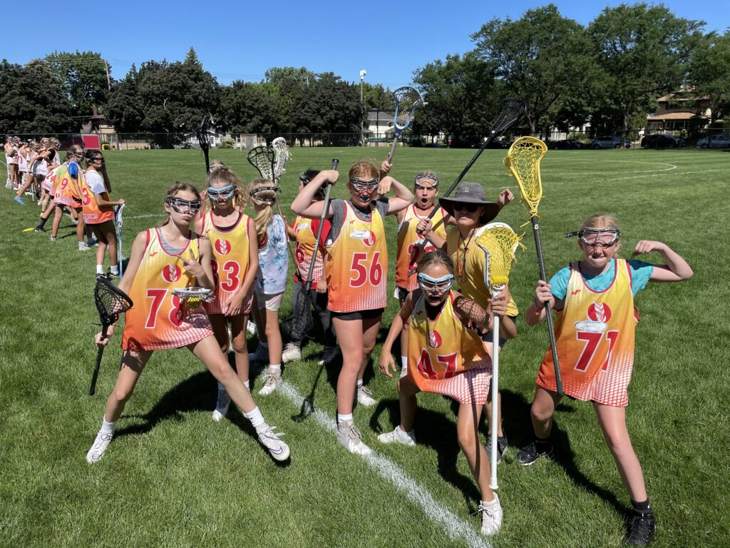 A group of girls, holding lacrosse sticks in a field.