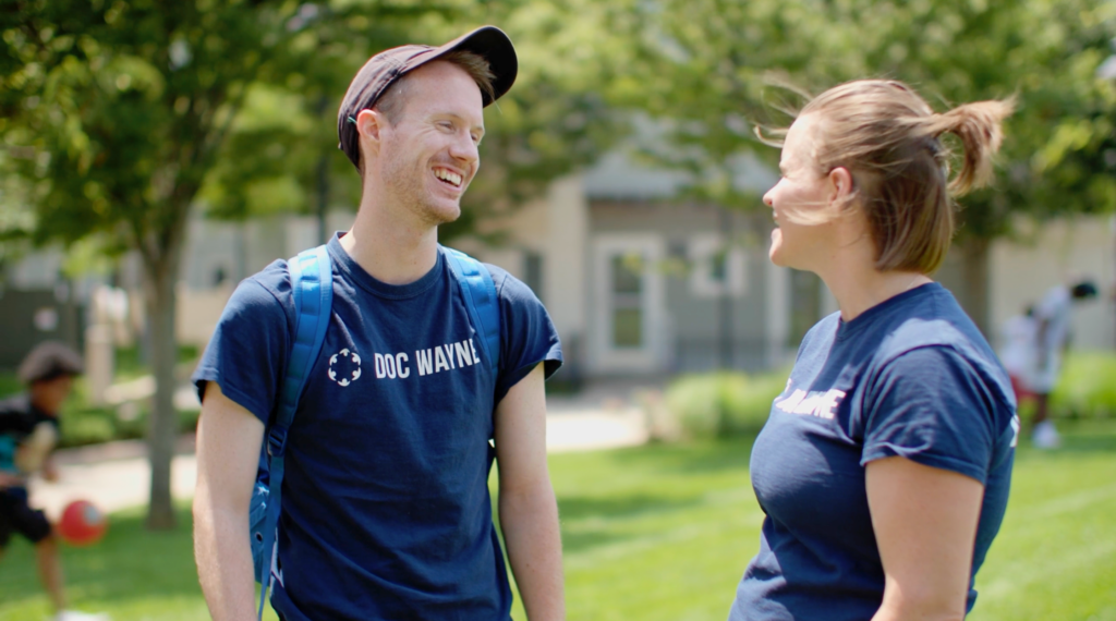 Man and women talking in an open field. They are happy.